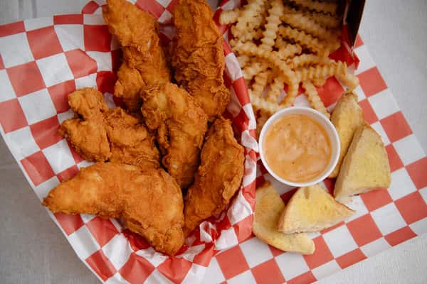 Basket of hand breaded chicken tenders served with cornbread and dipping sauce.