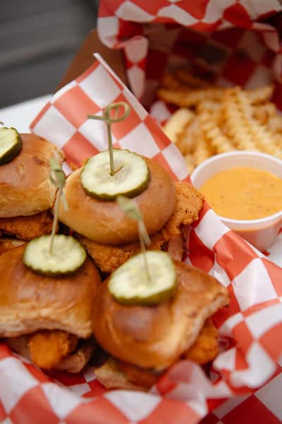 Close up of a fried chicken sandwich with pickle slices and creamy sauce.