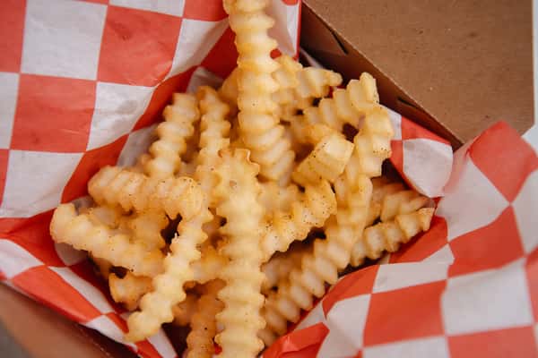 Basket of golden crinkle cut fries.