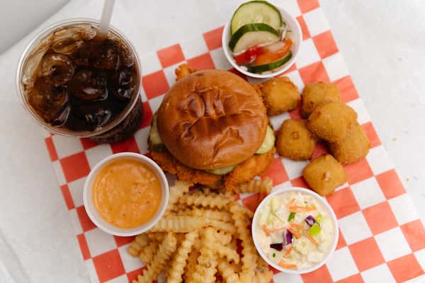Chicken sandwich platter with fries, hush puppies, coleslaw, and a fountain drink.