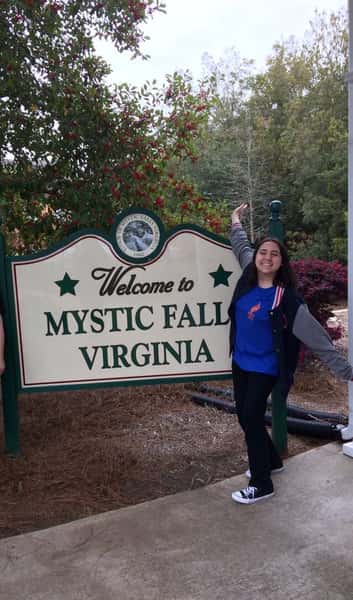 person by Mystic Falls Virginia sign