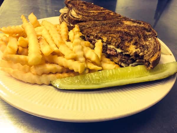 A sandwich served with fries and pickle
