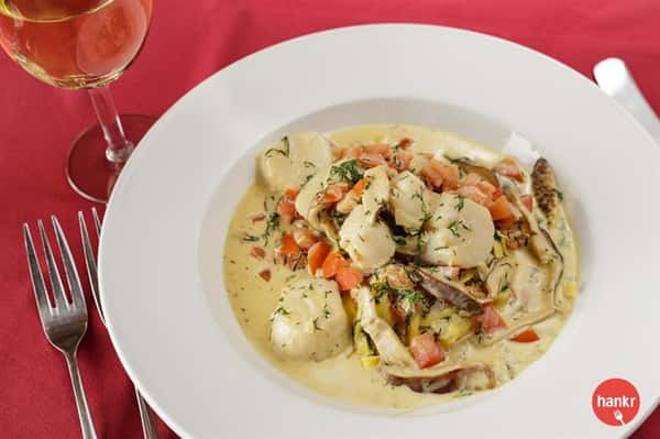 A white sauce dish served with a glass of white wine