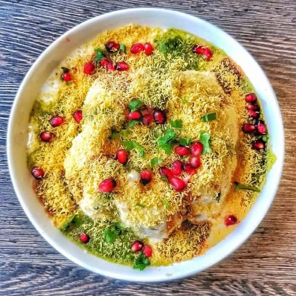 a bowl filled with fried dough topped with garnish and pomegranates