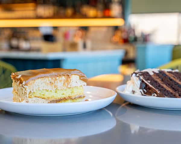 Dessert slices on plates, including a layered cake slice, on a table.