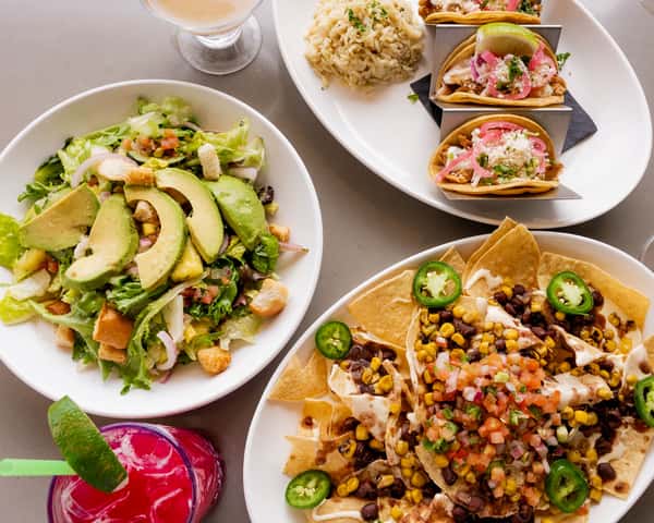 A vibrant spread of fusion tacos, coconut shrimp, and island rice on a wooden table.