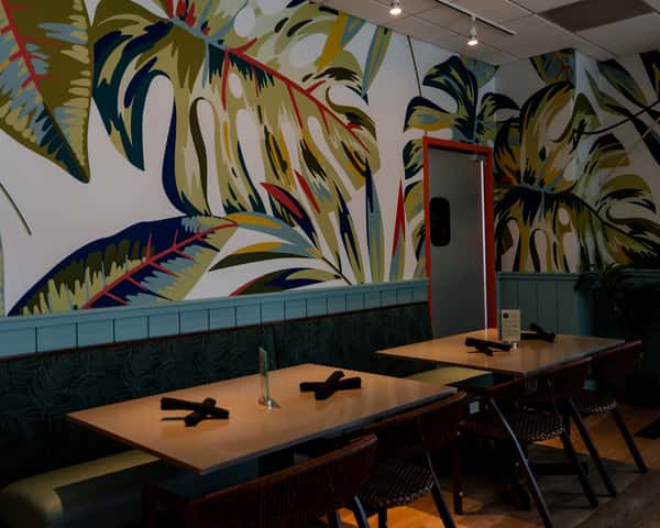 Restaurant booth seating area with a tropical mural on the wall.