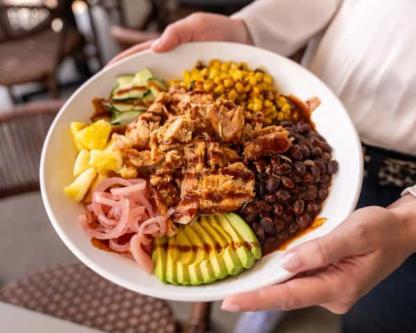 Close up of a bowl with rice, beans, shredded meat, and pickled onions.