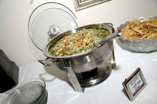 metal catering display of spinach and artichoke dip with a side of chips
