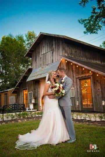 bride and groom taking wedding photos together standing outside a wooden barn