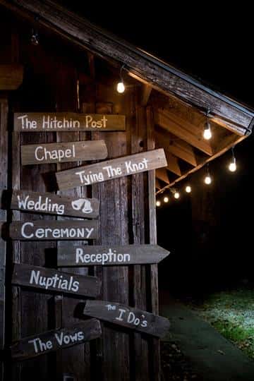 various wood signs hanging on a barn that point to directions around the establishment