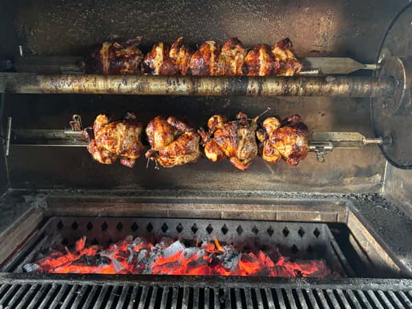 Chicken pieces grilling over open flames inside a barbecue grill.
