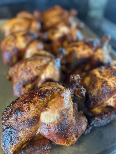 Close-up of roasted chicken with crispy, seasoned skin.