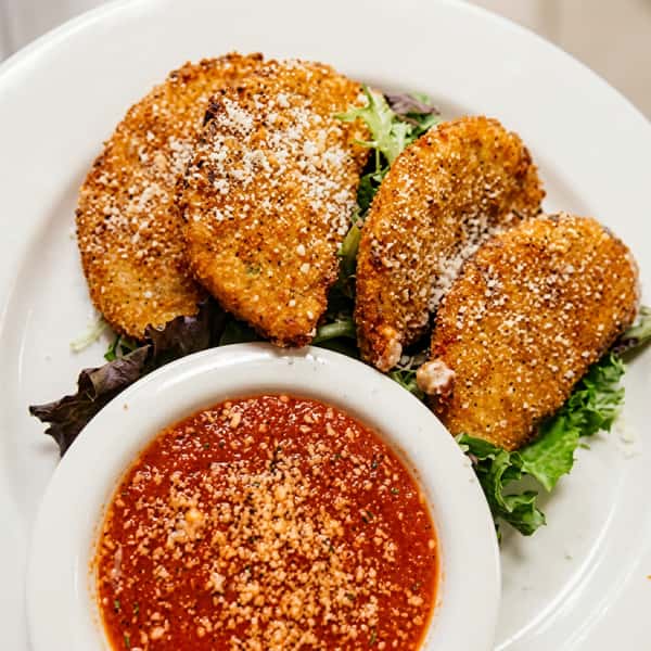 Crispy breaded cheese ravioli served with marinara dipping sauce, grated Parmesan, and fresh mixed greens.