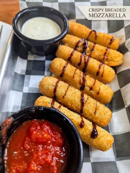 Crispy breaded mozzarella sticks served with marinara sauce and creamy ranch dipping sauce, finished with a balsamic glaze drizzle.