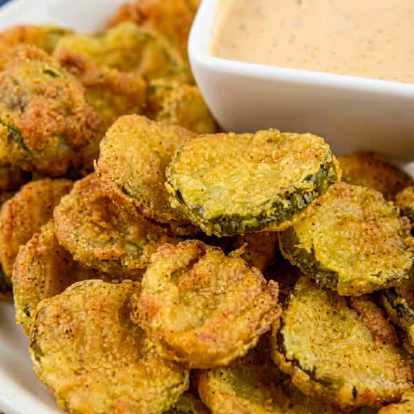 Crispy fried pickle chips served hot with a creamy house dipping sauce for a flavorful appetizer.