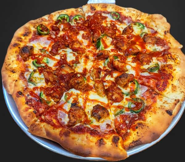 Buffalo chicken pizza topped with grilled chicken, jalapeños, mozzarella, smoky bacon, and a drizzle of spicy buffalo sauce on a hand-tossed crust.