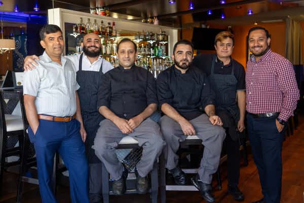 A group of chefs in uniforms posing together for a photo in a restaurant setting.