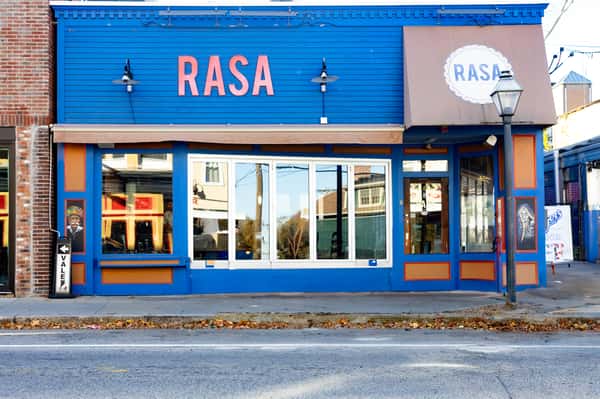 A close-up of the restaurant's exterior, highlighting the entrance with large windows and blue trim, labeled with "Rasa.