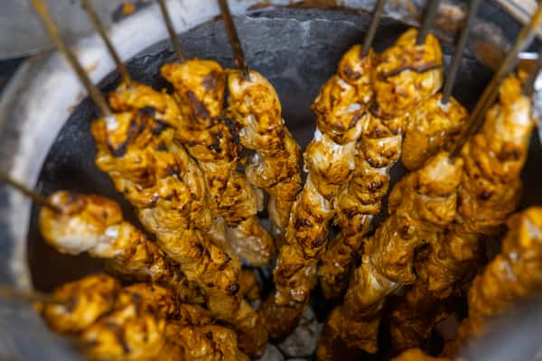 Skewers of marinated chicken cooking on a grill, showcasing the meat before serving.