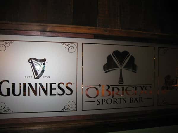 Two smoked glass dividers, one having Guinness beer trade mark and other with O'Briens sports bar