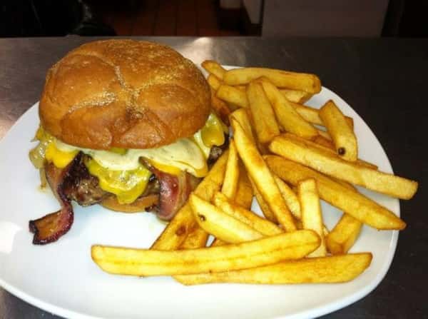 A cheeseburger with bacon served with French fries