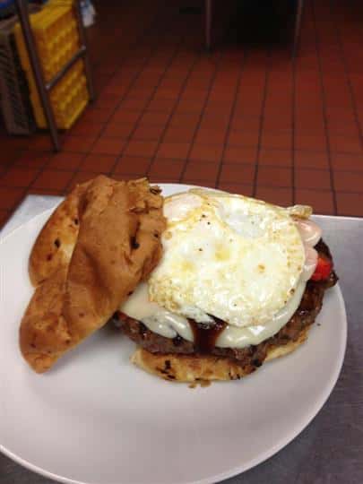 An open faced burger topped with Applewood smoked bacon, sharp cheddar and a fried egg