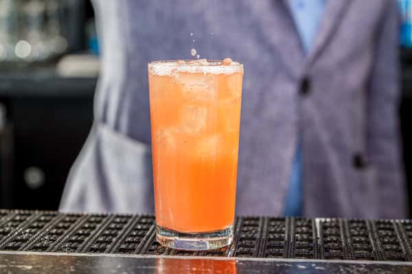 Whiskey Charlie signature cocktail held against waterfront views of The Wharf in Washington, DC