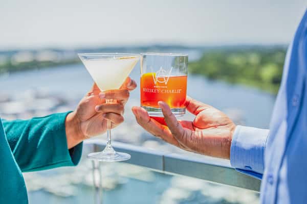 Whiskey Charlie signature cocktail held against waterfront views of The Wharf in Washington, DC