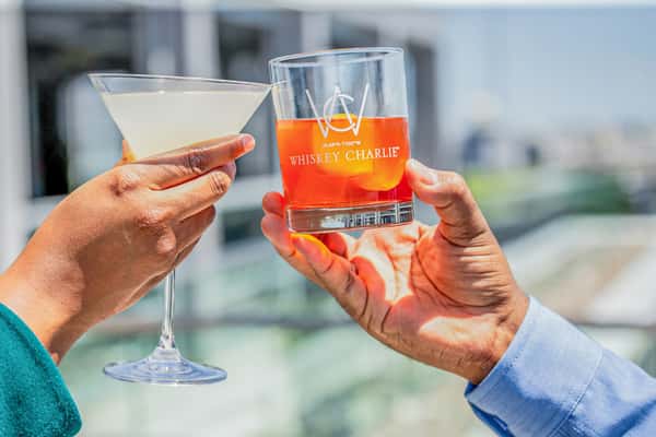 Whiskey Charlie signature cocktail held against waterfront views of The Wharf in Washington, DC