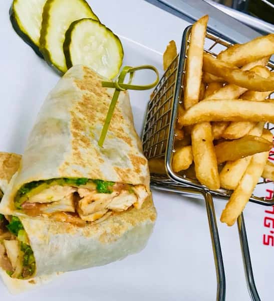 Chicken burrito with yellow peppers and lettuce with a side of fries