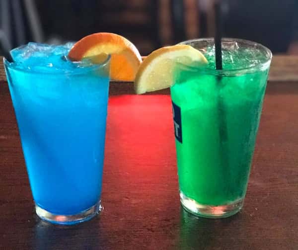 A blue and a green cockatils with oranges hanging off the side