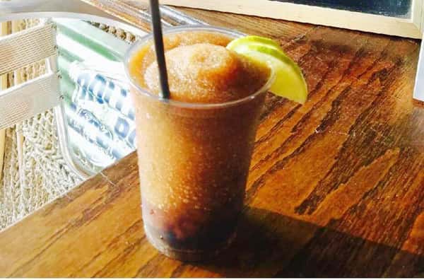 Orange frozen cocktail with lime hanging off the side