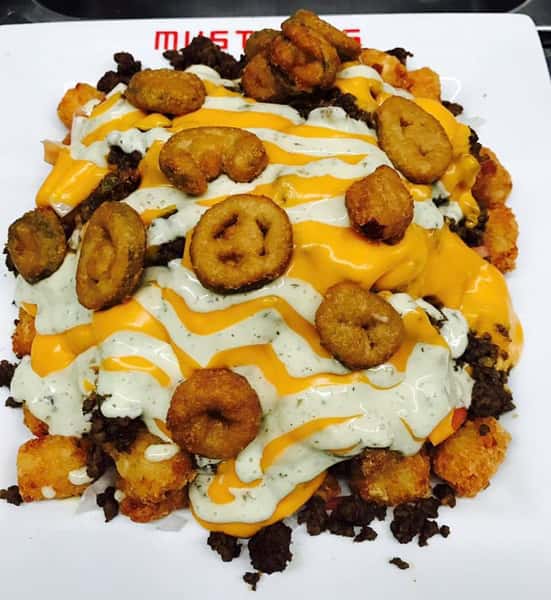 Tater Tots layered with ground beef, creamy cheese sauce, fresh diced tomatoes and onions, and a drizzle of jalapeno ranch sauce
