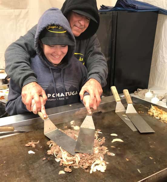 man teaching girl how to cook on a grill