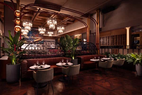 Luxury modern restaurant dining room with leather booths, chandeliers, and indoor plants