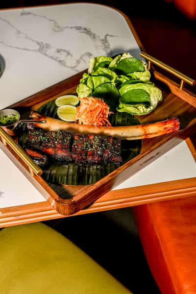 Roasted ribs platter with lettuce wraps, lime, pickled vegetables, and herb sauce.