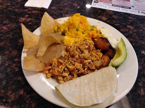 two soft tacos with chicken, avocado slices and a side of rice with tortilla chips