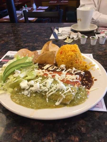 enchiladas with three difference sauces, a side of lettuce and rice with tortilla chips