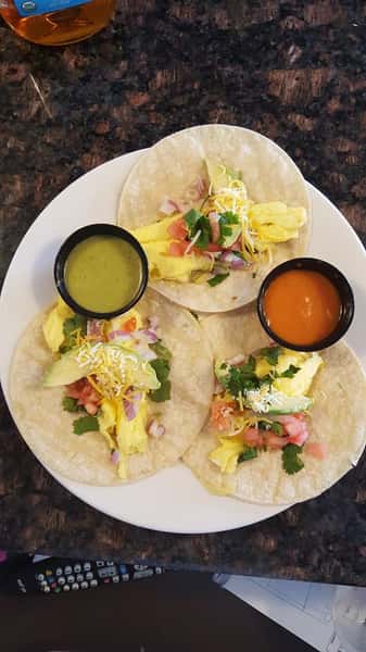 three open soft tacos with cilantro and tomatoes