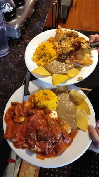 Two dishes with refried beans, rice and tortilla chips.
