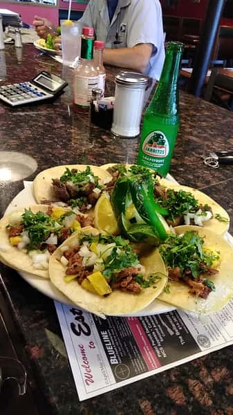 Six Tacos al Pastor or Lengua, soft tacos marinated pork with grilled pineapples or lengua with onions, cilantro, both served with rice & beans