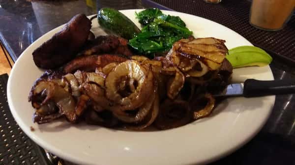 steak served with sauteed onions and a side of potatoes and sauteed spinach