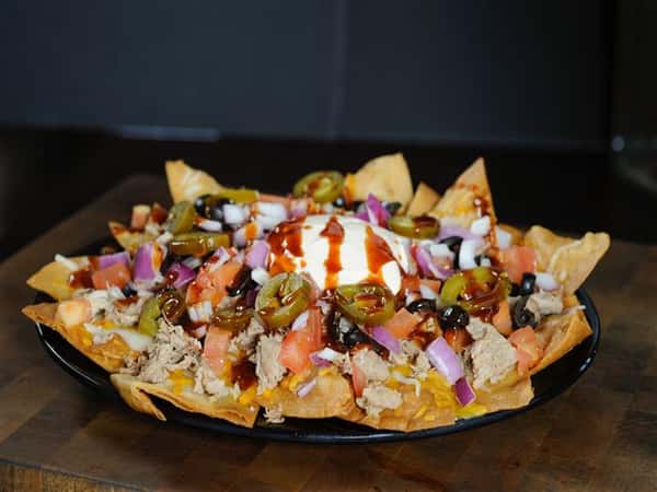 Corn chips topped with smoked shredded chicken cheddar and mozzarella cheeses, olives jalapenos, onions, tomatoes and seasoned sour cream