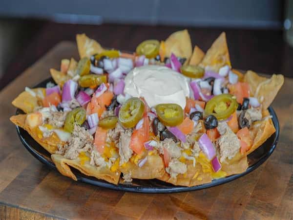 Corn chips topped with smoked shredded pork, cheddar and mozzarella cheeses, olives jalapenos, onions, tomatoes and seasoned sour cream