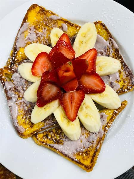 French toast topped with bananas, strawberries and powdered sugar