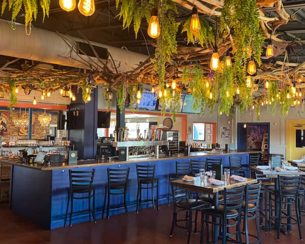 Inviting bar and dining interior at Lou Lou in Middletown, Louisville, with warm lighting, greenery, and rustic charm.
