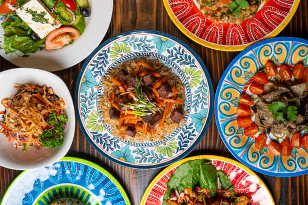A vibrant spread of halal dishes, featuring flavorful rice topped with tender beef and carrots, fresh salad, colorful appetizers, and garnished plates.