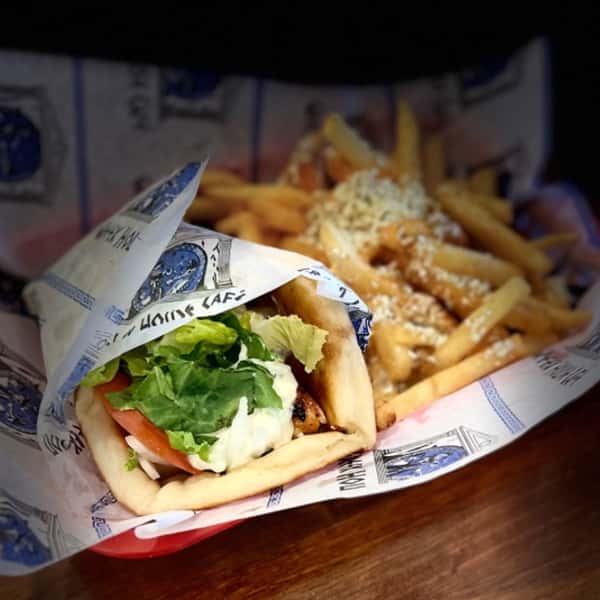Chicken gyro wrap with lettuce, tomato, and tzatziki, served with a side of feta-topped fries in a red basket.