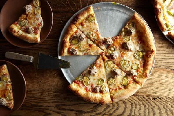 Pizza on a table with two slices on plates with a serving spatula